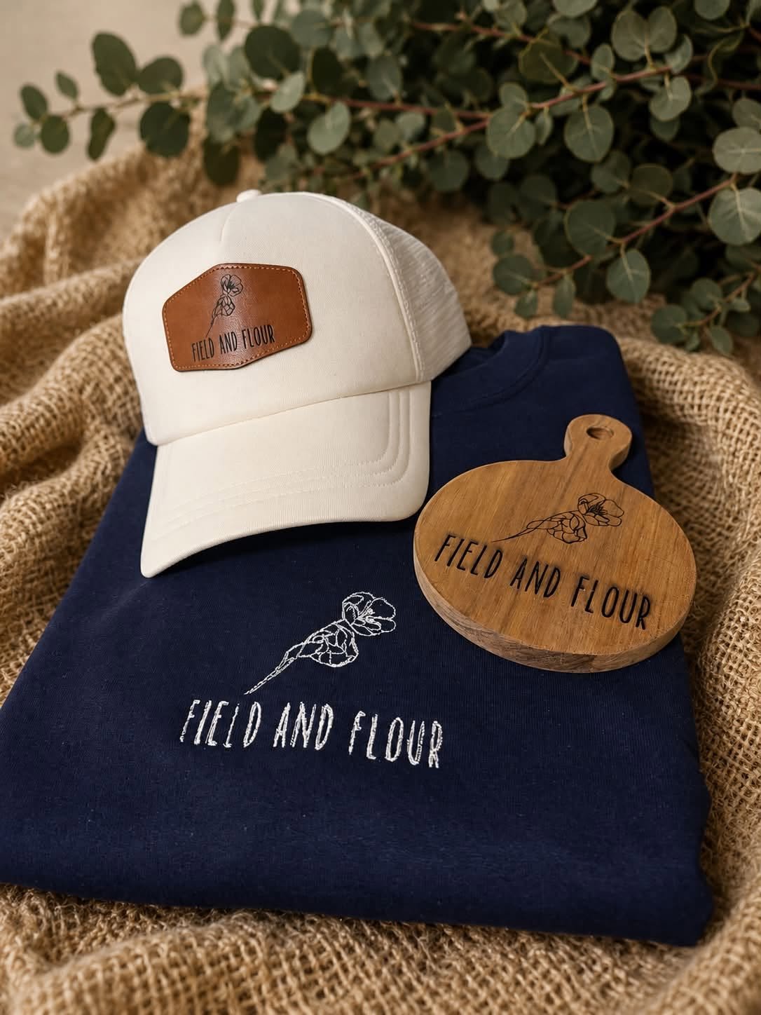 Cream trucker hat with a leather patch and navy embroidered sweatshirt for Field and Flour