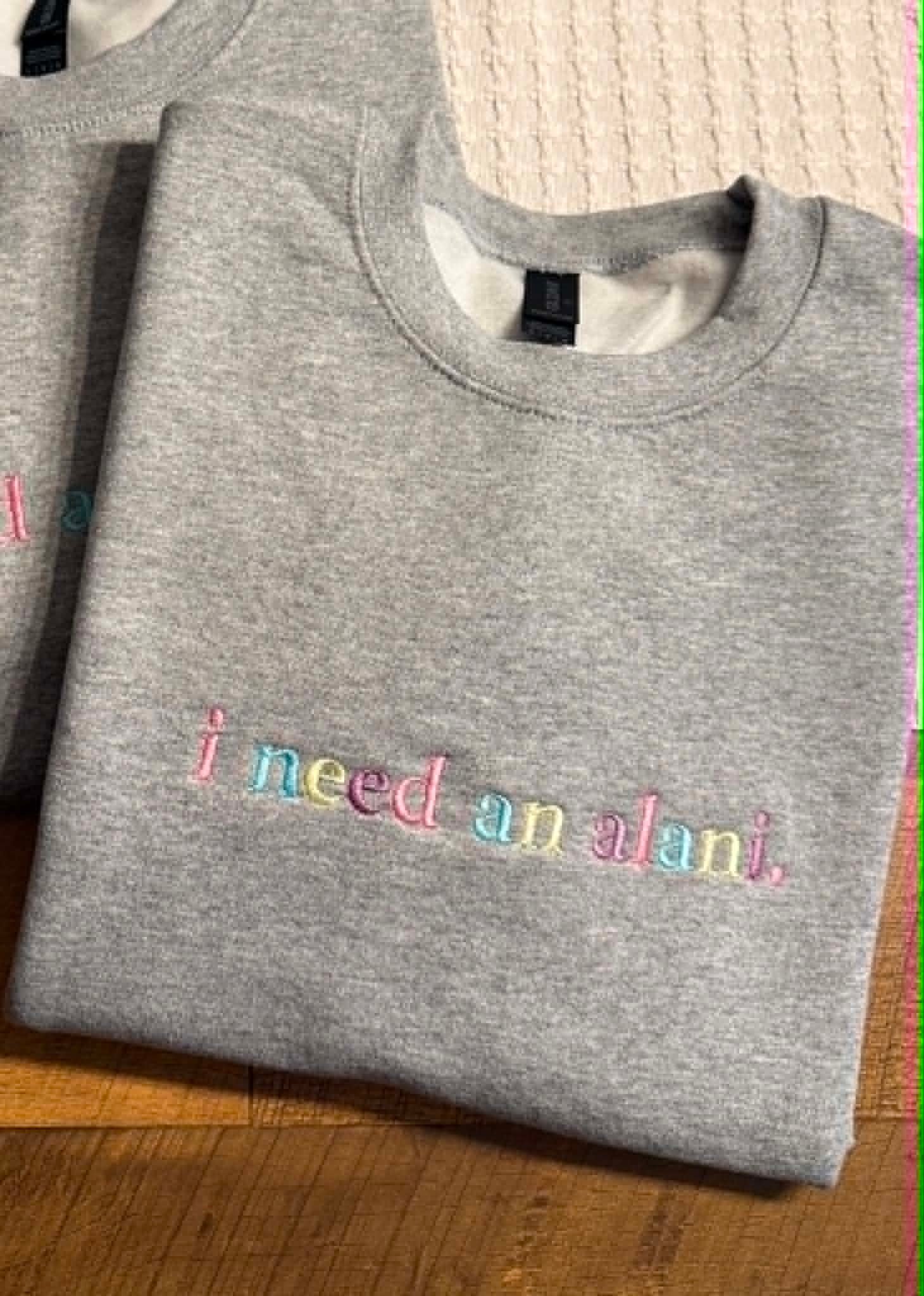 Heather grey Gildan crewneck embroidered in rainbow pastel lettering reading i need an alani