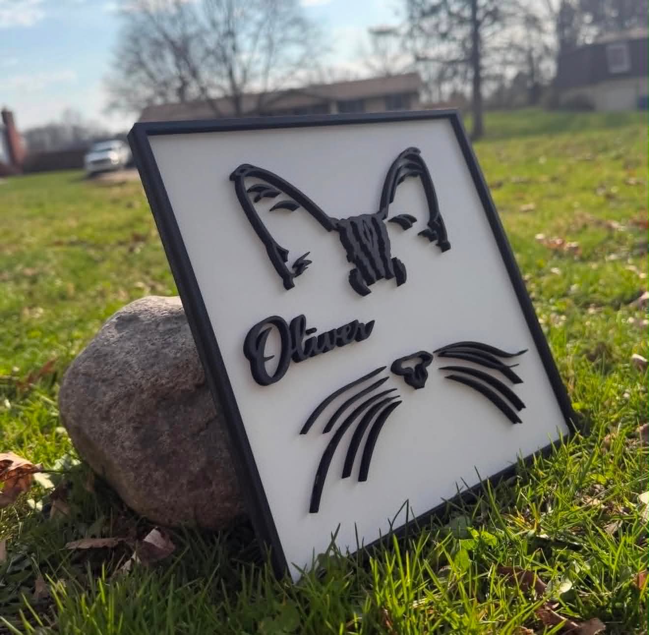 Square sign with a line-art cat face and the name Oliver